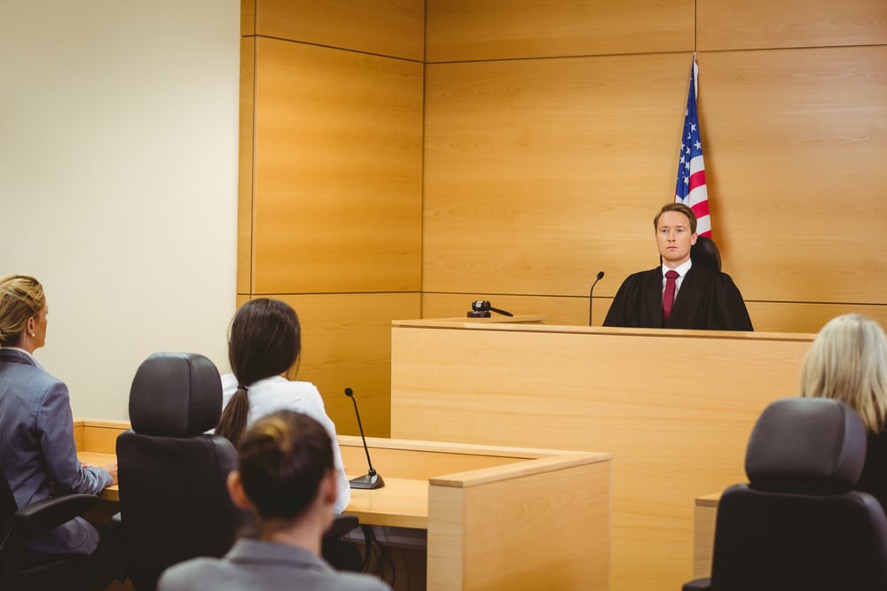 Unsmiling judge with american flag behind him in the court room Unsmiling judge with american flag behind him in the court room