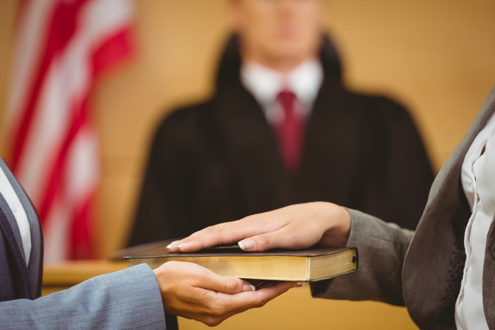 Witness swearing on the bible telling the truth in the court room Witness swearing on the bible telling the truth in the court room